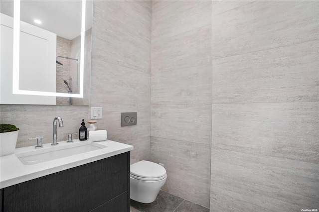 bathroom featuring tile patterned floors, vanity, toilet, and tile walls