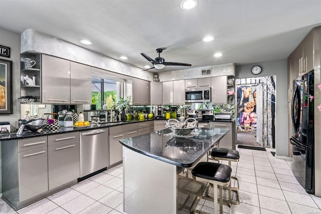 kitchen with gray cabinetry, sink, a kitchen breakfast bar, a kitchen island, and black appliances