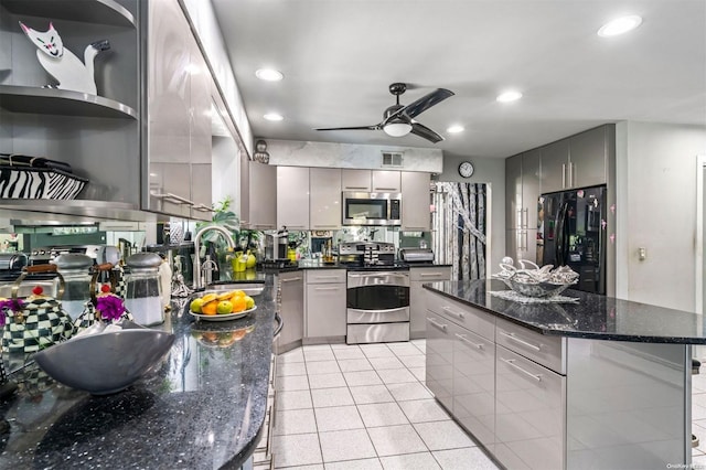 kitchen with appliances with stainless steel finishes, gray cabinets, dark stone counters, and sink