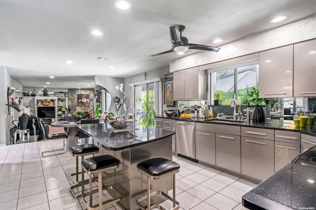 kitchen featuring gray cabinetry, dishwasher, a kitchen breakfast bar, and dark stone counters