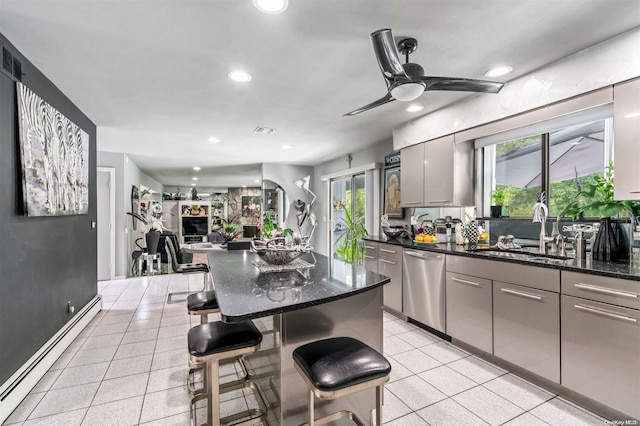 kitchen with dishwasher, sink, baseboard heating, gray cabinets, and a breakfast bar