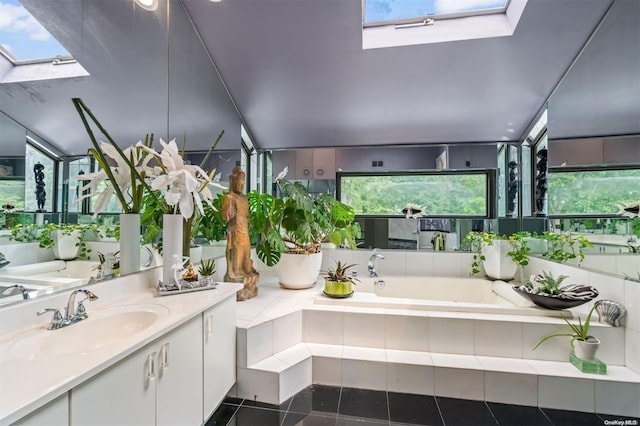 bathroom featuring vanity, a skylight, tile patterned floors, and a relaxing tiled tub