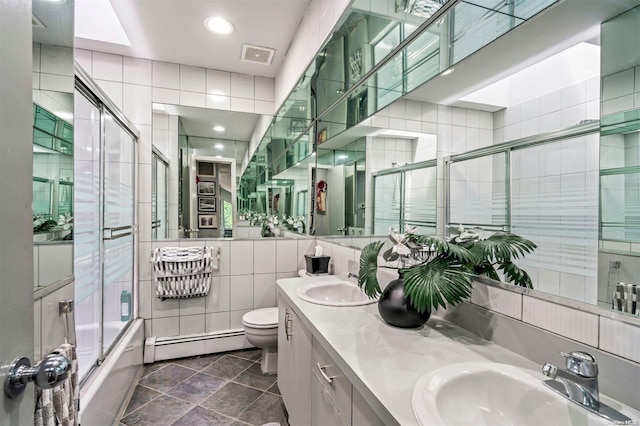 full bathroom with a baseboard radiator, tile patterned floors, bath / shower combo with glass door, toilet, and tile walls