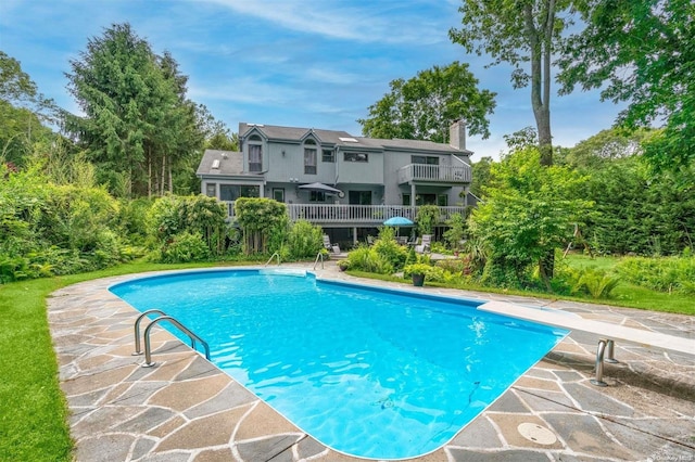 view of swimming pool with a diving board and a patio