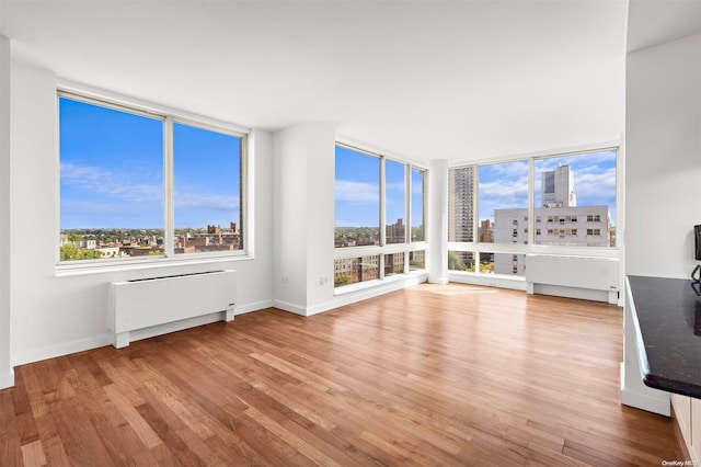 unfurnished living room featuring radiator heating unit and light wood-type flooring