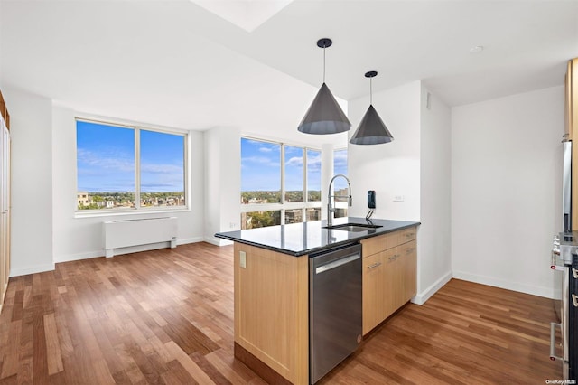 kitchen featuring light brown cabinets, hanging light fixtures, sink, stainless steel dishwasher, and hardwood / wood-style flooring