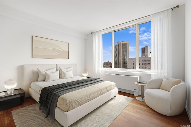 bedroom with radiator and hardwood / wood-style floors