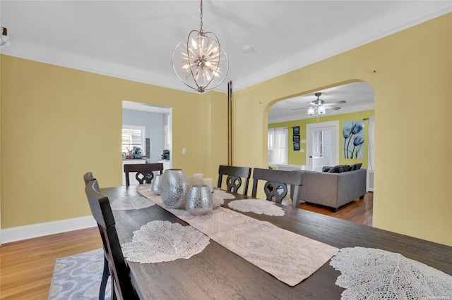 dining area featuring hardwood / wood-style floors, ceiling fan with notable chandelier, and crown molding