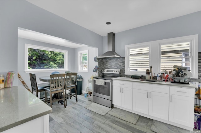 kitchen with stainless steel electric range oven, sink, light stone countertops, wall chimney range hood, and white cabinets