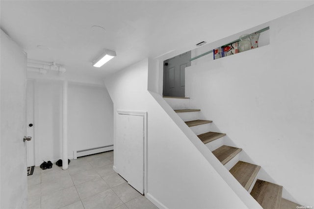 stairway with tile patterned floors and baseboard heating