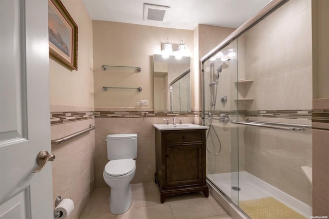 bathroom featuring an enclosed shower, vanity, tile patterned floors, and tile walls