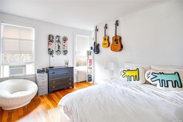 bedroom with radiator, light hardwood / wood-style flooring, and cooling unit