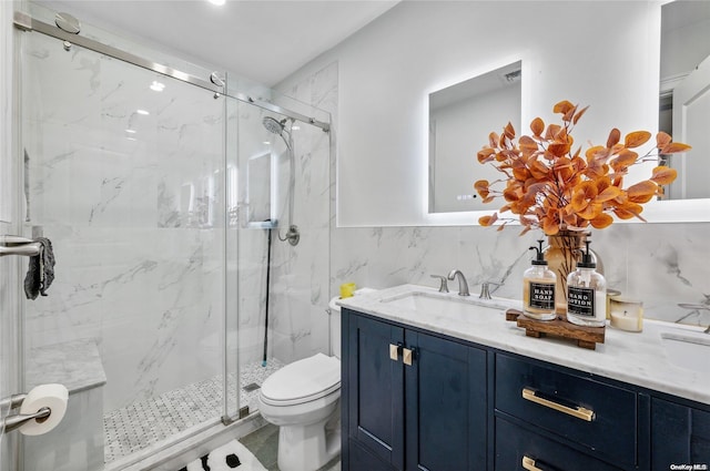 bathroom featuring vanity, toilet, a shower with shower door, and tile walls