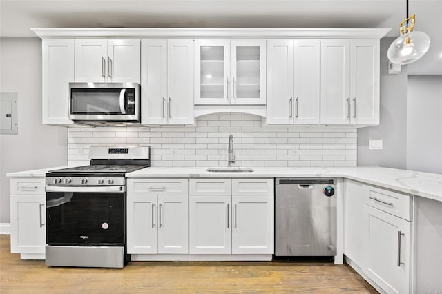 kitchen featuring light stone countertops, appliances with stainless steel finishes, sink, decorative light fixtures, and white cabinetry