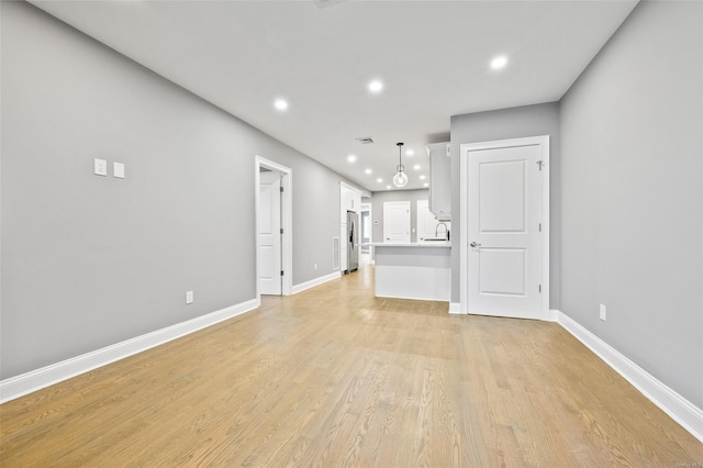 unfurnished living room with light wood-type flooring and sink