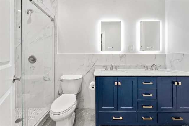 bathroom with a shower with door, vanity, tile walls, and toilet