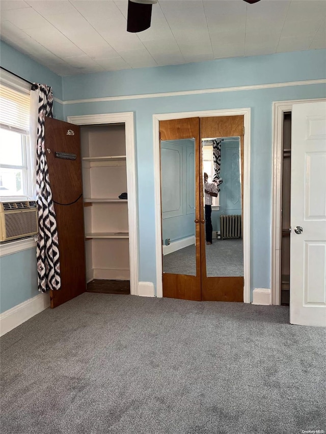 unfurnished bedroom with cooling unit, ceiling fan, radiator heating unit, and carpet floors