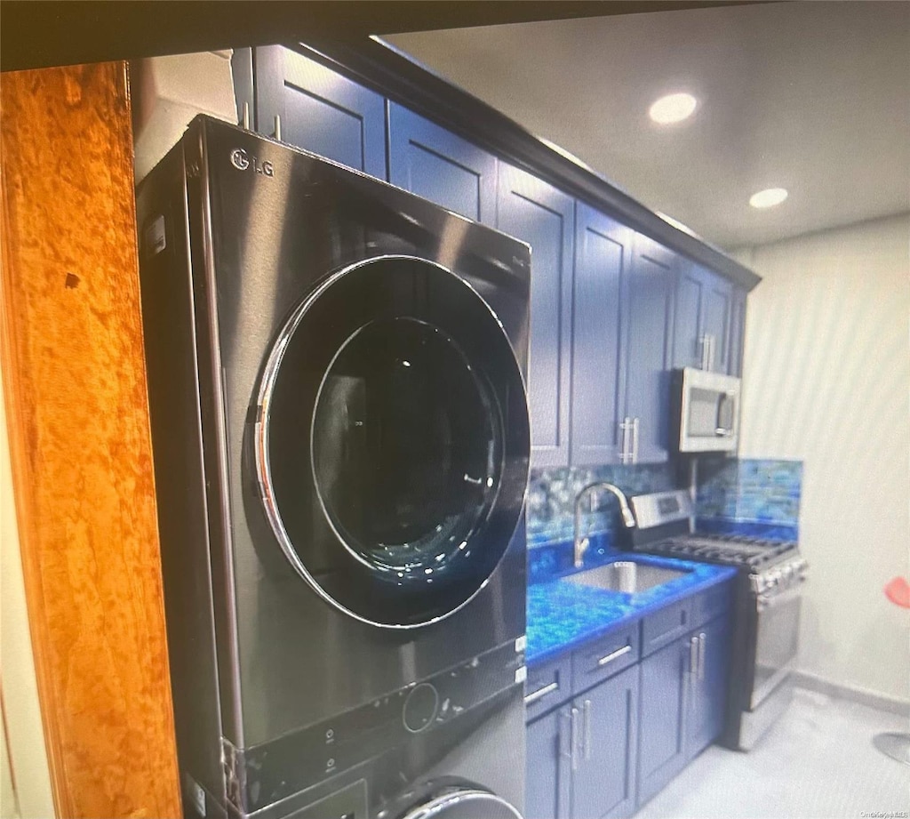 clothes washing area featuring sink and stacked washing maching and dryer