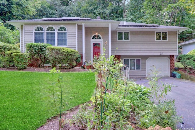 raised ranch with a front yard, solar panels, and a garage