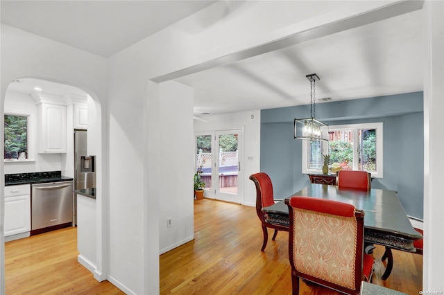 dining space featuring a chandelier, light hardwood / wood-style flooring, a wealth of natural light, and a baseboard heating unit