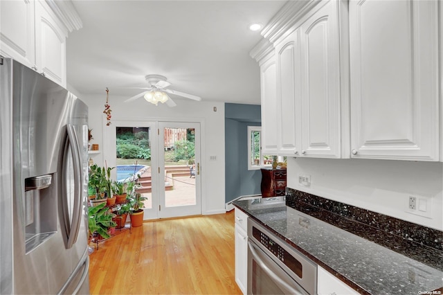 kitchen featuring appliances with stainless steel finishes, dark stone counters, ceiling fan, light hardwood / wood-style flooring, and white cabinets