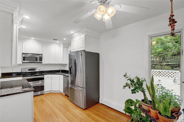 kitchen featuring white cabinetry, ceiling fan, dark stone counters, light hardwood / wood-style floors, and appliances with stainless steel finishes