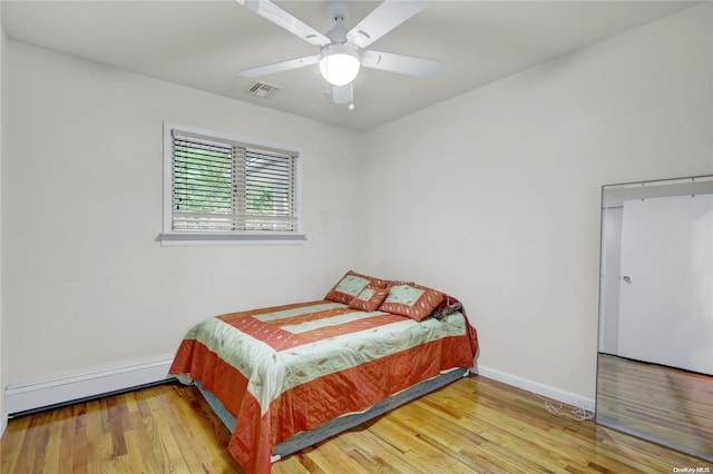 bedroom featuring ceiling fan, hardwood / wood-style floors, and a baseboard radiator