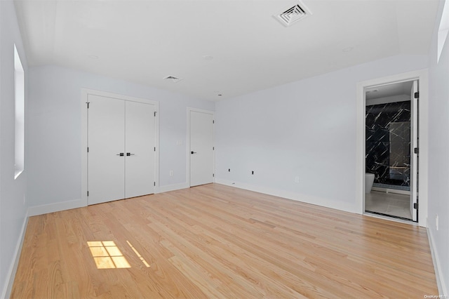 unfurnished bedroom with light wood-type flooring and ensuite bathroom