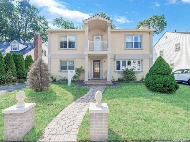 view of front of property with a balcony and a front lawn