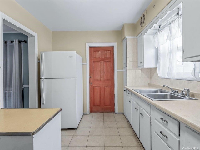 kitchen featuring white cabinets, light tile patterned floors, white fridge, and sink