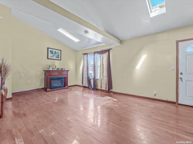 unfurnished living room with vaulted ceiling with skylight and light hardwood / wood-style floors