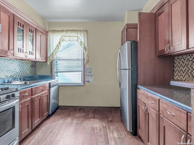 kitchen with backsplash, sink, light hardwood / wood-style floors, and appliances with stainless steel finishes