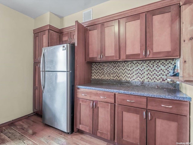 kitchen featuring backsplash, stainless steel refrigerator, and light hardwood / wood-style floors