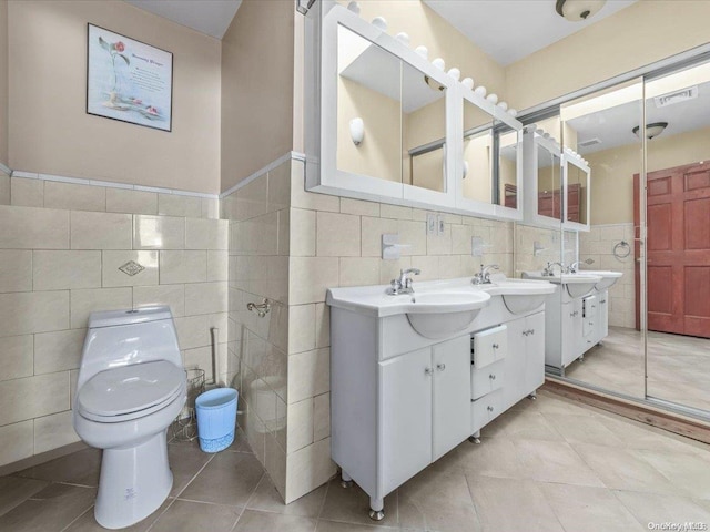 bathroom with tile patterned flooring, vanity, toilet, and tile walls