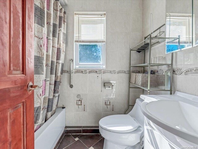 full bathroom featuring shower / bath combo, tile patterned floors, toilet, vanity, and tile walls