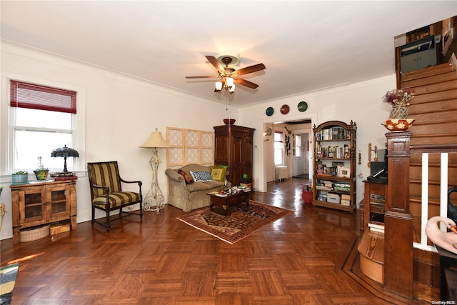 living room with ceiling fan, crown molding, and dark parquet floors