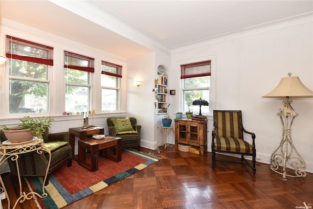 sitting room featuring a healthy amount of sunlight, dark parquet flooring, and crown molding