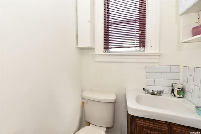 bathroom featuring vanity, toilet, and backsplash