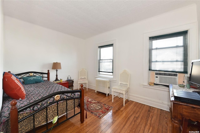 bedroom with hardwood / wood-style flooring, radiator, and cooling unit