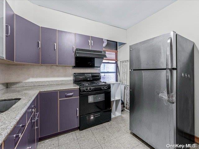 kitchen featuring dark brown cabinetry, range hood, black range with gas cooktop, and stainless steel refrigerator