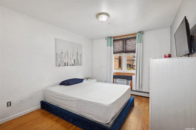 bedroom featuring wood-type flooring and a baseboard radiator