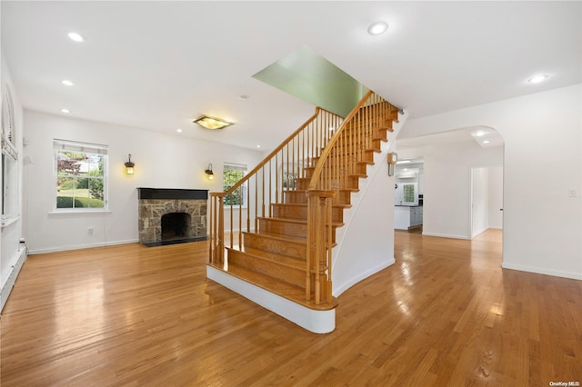 unfurnished living room featuring a stone fireplace and light hardwood / wood-style flooring