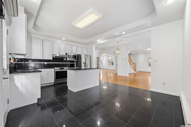 kitchen featuring white cabinets, sink, stainless steel appliances, and a tray ceiling