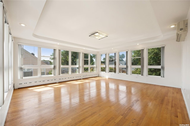 unfurnished sunroom with baseboard heating, a raised ceiling, and a wall unit AC