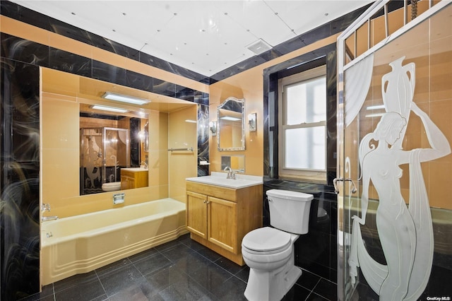 bathroom featuring a bath, vanity, toilet, and tile walls