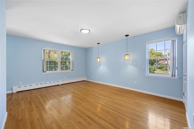 spare room with light wood-type flooring, an AC wall unit, and baseboard heating