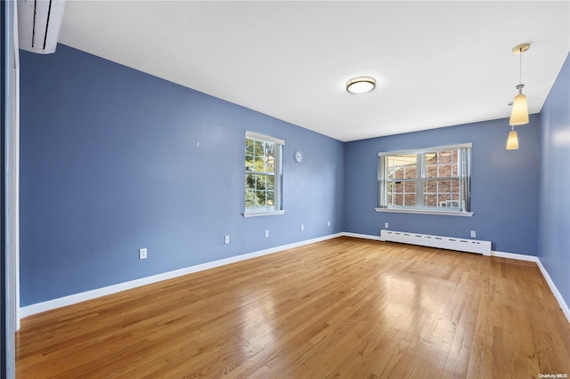 spare room with hardwood / wood-style floors, a healthy amount of sunlight, and baseboard heating