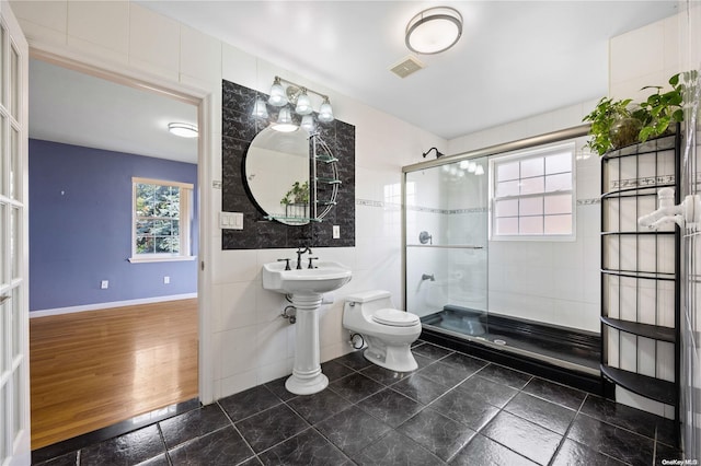 bathroom with wood-type flooring, sink, toilet, tile walls, and a shower with shower door