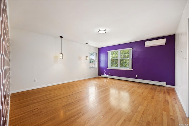 spare room featuring an AC wall unit, light wood-type flooring, and a baseboard heating unit