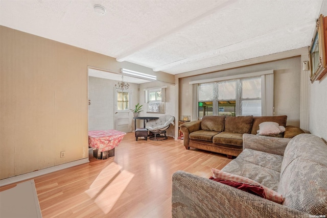 living room featuring beamed ceiling, a textured ceiling, hardwood / wood-style flooring, and an inviting chandelier